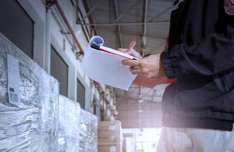 worker checking his list on clipboard in a large warehouse